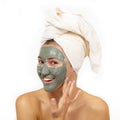 Beautiful cheerful teen girl applying facial clay mask. Beauty treatments, isolated over white Royalty Free Stock Photo