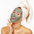 Beautiful cheerful teen girl applying facial clay mask. Beauty treatments, isolated over white Royalty Free Stock Photo