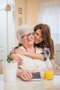 Beautiful cheerful teenage girl hugging her old grandmother. Royalty Free Stock Photo