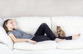 Beautiful cheerful woman lying on sofa with bengal cat