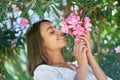 Beautiful cheerful woman touching pink flowers and enjoying smell in spring garden Royalty Free Stock Photo