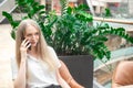 Portrait of a cheerful young caucasian blond business woman sitting on the table, talking at phone and smiling. Surprised face. Royalty Free Stock Photo