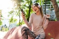 Beautiful cheerful young fitness sports woman posing outdoors in park listening music with earphones using mobile phone Royalty Free Stock Photo