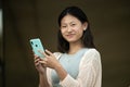 Beautiful cheerful young lady looking at camera texting and standing outside.Joyful carefree woman staring at camera in