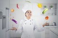 Beautiful chef juggling food ingredients in kitchen Royalty Free Stock Photo