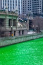Beautiful Chicago architcture along a dyed green Chicago River where crowds gather