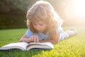 Beautiful child boy book on grass background. Kids reading book in park. Royalty Free Stock Photo