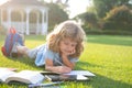 Beautiful child boy with book writing notes in copybook on grass background. Kids reading book in park. Royalty Free Stock Photo