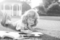 Beautiful child boy with book writing notes in copybook on grass background. Kids reading book in park.