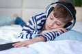 Beautiful child boy lies on the bed and listens to music and enjoys. He closed his eyes from dreams or fell asleep Royalty Free Stock Photo