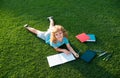 Beautiful child boy writing on notebook on grass background. Kids reading book in park. Concept of kids learning, study Royalty Free Stock Photo