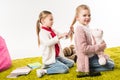 beautiful child brushing hair of sister while she sitting on floor with toy bunny Royalty Free Stock Photo