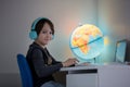 Beautiful child with earphones using laptop while studying at desk at home Royalty Free Stock Photo