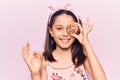 Beautiful child girl holding cookie doing ok sign with fingers, smiling friendly gesturing excellent symbol Royalty Free Stock Photo