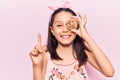 Beautiful child girl holding cookie smiling with an idea or question pointing finger with happy face, number one Royalty Free Stock Photo