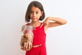 Beautiful child girl holding jar of cookies standing over isolated white background with surprise face pointing finger to himself Royalty Free Stock Photo