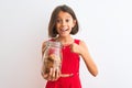 Beautiful child girl holding jar of cookies standing over isolated white background very happy pointing with hand and finger Royalty Free Stock Photo