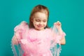Beautiful child girl holding lace hem of her pink dress on blue isolated Royalty Free Stock Photo