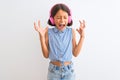 Beautiful child girl listening to music using headphones over isolated white background celebrating mad and crazy for success with Royalty Free Stock Photo