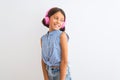 Beautiful child girl listening to music using headphones over isolated white background looking away to side with smile on face, Royalty Free Stock Photo