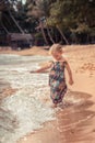 Beautiful child girl playing with waves on beach tropical island during summer holidays concept carefree childhood travel lifestyl Royalty Free Stock Photo