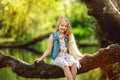 Beautiful child girl sitting on log under river outdoors