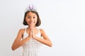 Beautiful child girl wearing princess crown standing over isolated white background praying with hands together asking for Royalty Free Stock Photo