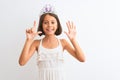 Beautiful child girl wearing princess crown standing over isolated white background showing and pointing up with fingers number