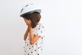 Beautiful child girl wearing security bike helmet standing over isolated white background with sad expression covering face with Royalty Free Stock Photo