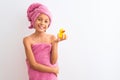 Beautiful child girl wearing shower towel holding duck over isolated white background with a happy face standing and smiling with Royalty Free Stock Photo