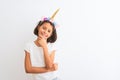 Beautiful child girl wearing unicorn diadem standing over isolated white background looking confident at the camera smiling with Royalty Free Stock Photo