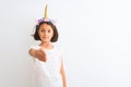 Beautiful child girl wearing unicorn diadem standing over isolated white background smiling friendly offering handshake as Royalty Free Stock Photo