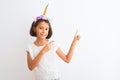 Beautiful child girl wearing unicorn diadem standing over isolated white background smiling and looking at the camera pointing Royalty Free Stock Photo