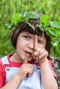 Beautiful child with a green ivy crown winking and playing