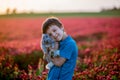 Beautiful child with cute bunny in gorgeous crimson clover field Royalty Free Stock Photo