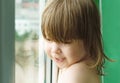 A beautiful child looks out the window. child at home.