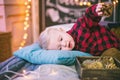 Beautiful child lying on the bed on pillows and plaid with a branch of cotton