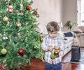 A beautiful child, play with two colored balls next to the Christmas tree in the living room Royalty Free Stock Photo