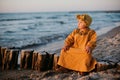 Beautiful child sitting on breakwater on baltic sea beach at sunrise time Royalty Free Stock Photo