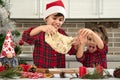 Beautiful children cooking together in the home kitchen during Christmas holidays. Adorable boy in Santa hat and his cute little