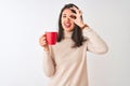 Beautiful chinese woman drinking red cup of coffee standing over isolated white background with happy face smiling doing ok sign Royalty Free Stock Photo