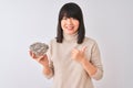 Beautiful chinese woman holding bowl with sunflowers seeds over isolated white background happy with big smile doing ok sign, Royalty Free Stock Photo