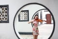 Beautiful Asian Chinese woman in traditional chi-pao cheongsam play violin in in a garden stand under arched door Royalty Free Stock Photo