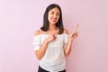 Beautiful chinese woman wearing white t-shirt standing over isolated pink background smiling and looking at the camera pointing Royalty Free Stock Photo