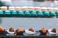 Beautiful chocolate small cakes at glass shop-window with colorful blurred macaroons on background