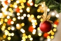 Beautiful Christmas ball hanging on fir tree branch against blurred lights, closeup. Space for text Royalty Free Stock Photo