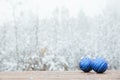 Beautiful Christmas bauble decorations lie on the wooden table over snow covered forest background Royalty Free Stock Photo