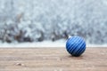 Beautiful Christmas bauble decorations lie on the wooden table over snow covered forest background Royalty Free Stock Photo