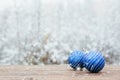 Beautiful Christmas bauble decorations lie on the wooden table over snow covered forest background. Royalty Free Stock Photo