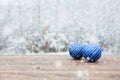 Beautiful Christmas bauble decorations lie on the wooden table over snow covered forest background. Royalty Free Stock Photo